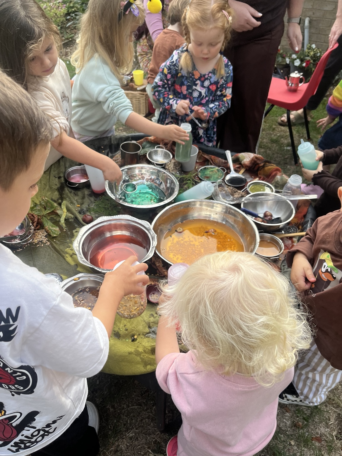 Little hands mixing colourful potions with bowls, spoons and containers