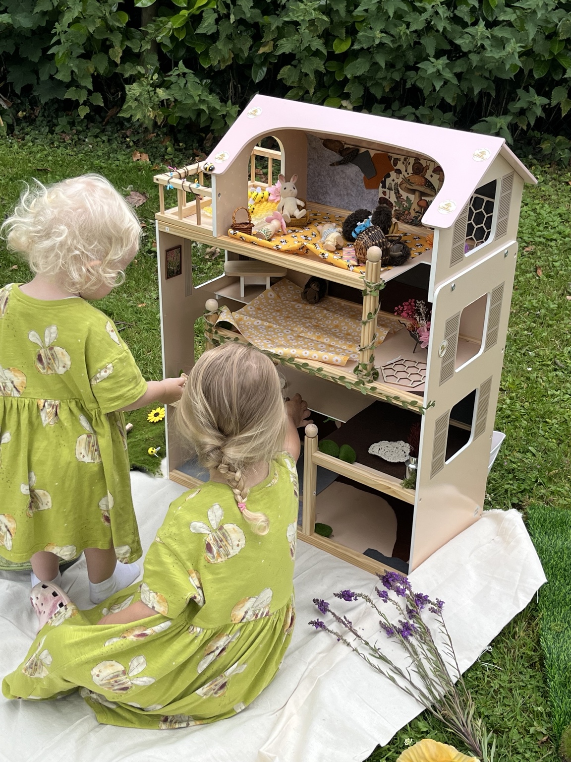 Two children exploring a dolls’ house decorated with woodland treasures