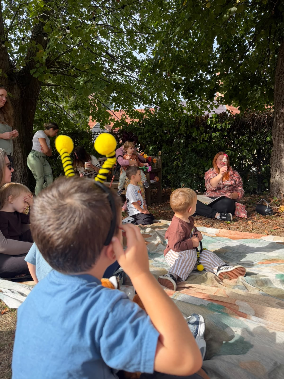 Children and grown-ups gathered on a mat with Jem and woodland puppets